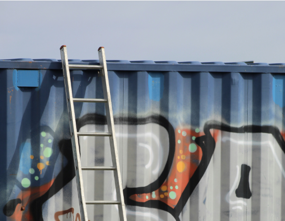 A ladder stands up against a shipping container.